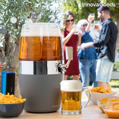 Distribuidor de bebidas com copo e snacks em mesa exterior com pessoas ao fundo