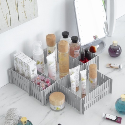 Organizador modular cinzento com produtos cosméticos com tampas de madeira sobre superfície marmoreada