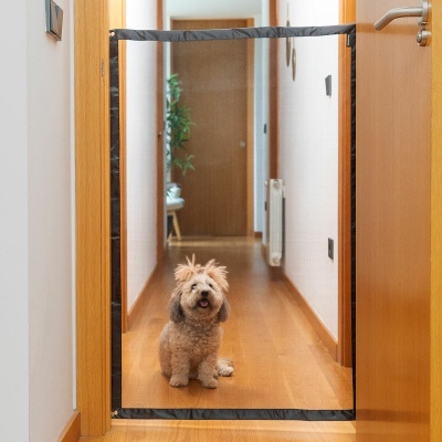 Porta de protecção em rede preta numa moldura de madeira a bloquear passagem de cão pequeno peludo num corredor