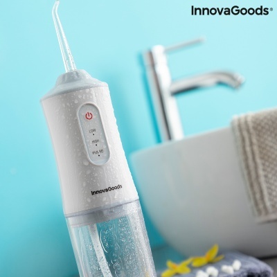 Irrigador oral branco InnovaGoods com botão e modos LOW, MID, PULSE junto a lavatório e toalha