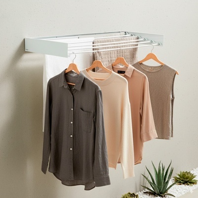 Estendal branco montado na parede com roupa e toalhas penduradas