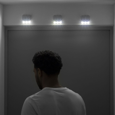 Três luzes LED acima de uma porta cinza escuro e homem de costas