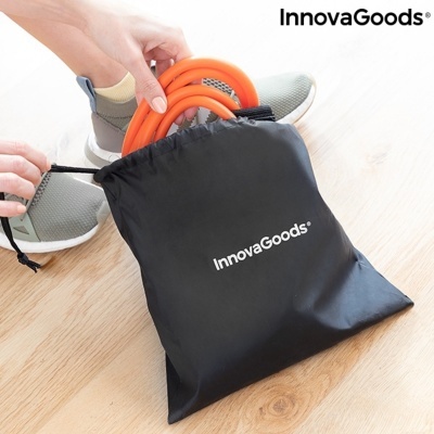 Bolsa preta InnovaGoods com acessório laranja e sapatos desportivos no chão de madeira