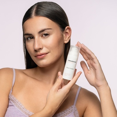 Mulher segurando frasco branco de creme facial Innovation Face Cream