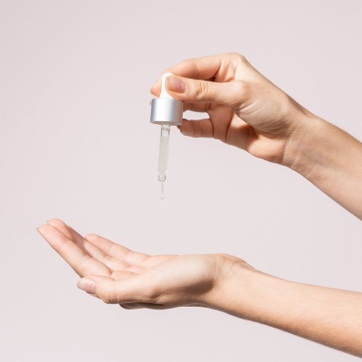 Mãos femininas com conta-gotas a despejar líquido transparente
