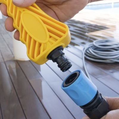 Conexão de mangueira amarela a acessório azul em chão de madeira