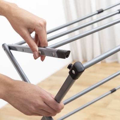 Montagem de estendal metálico prateado com pontas de plástico preto em chão de madeira