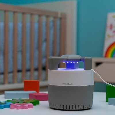 Purificador ou armadilha de insetos InnovaGoods cinzento e branco com luz LED azul numa mesa numa divisão infantil