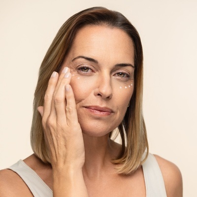 Mulher aplica creme ao redor do olho direito