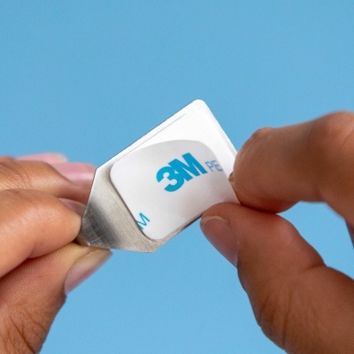 Etiqueta adesiva 3M a ser destacada de uma folha por duas mãos