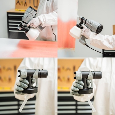 Pistola de pintura elétrica cinza com copo branco aplicando tinta vermelha em parede