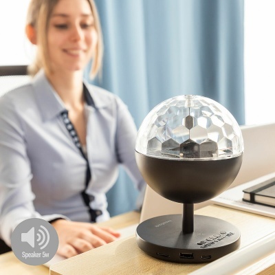 Coluna de som preta com cúpula acrílica facetada, sobre mesa de madeira em escritório