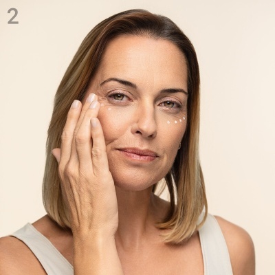 Mulher aplica creme ao redor do olho