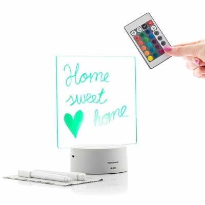 Quadro luminoso branco com texto 'Home sweet home' e controlo remoto colorido na mão