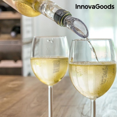 Duas taças de vinho branco com vinho sendo servido de garrafa com bocal transparente