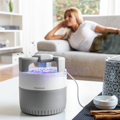 Mosquito repellent InnovaGoods branco e cinzento com luz UV azul numa sala de estar