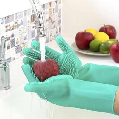 Luvas turquesa de silicone a lavar maçã vermelha debaixo de torneira