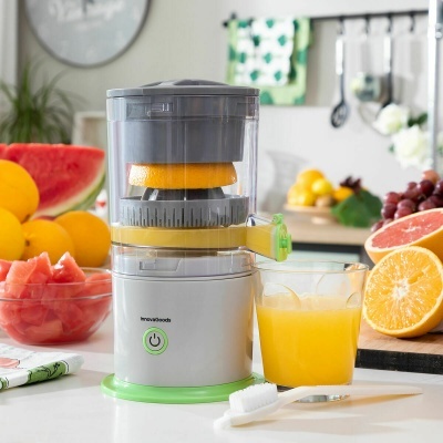 Máquina de sumos com frutas e copo de sumo na cozinha
