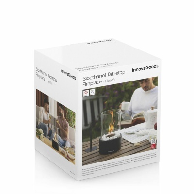 Embalagem branca de lareira de mesa bioetanol preta InnovaGoods com pedras brancas numa mesa de madeira