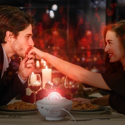 Jantar romântico com difusor branco de luz vermelha na mesa entre pratos e taças