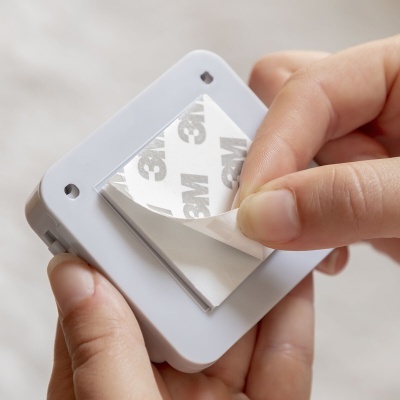 Dispositivo branco com autocolante 3M a ser descolado por mãos