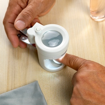 Dispositivo branco portátil com lente de aumento a analisar pele do dedo