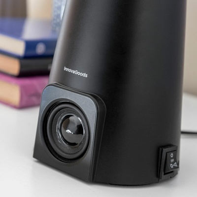 Coluna de som preta InnovaGoods sobre mesa branca com livros desfocados ao fundo