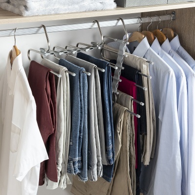 Varão de armário com camisas e calças penduradas em cabides de madeira e varão multi-calças metálico