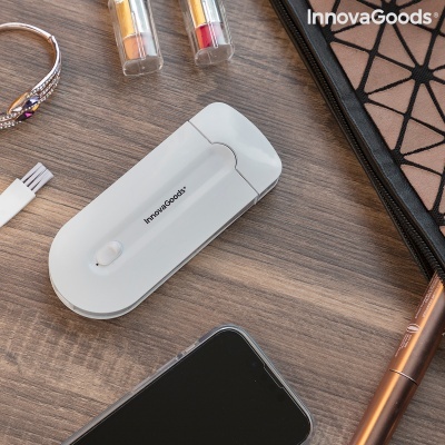 Dispositivo branco InnovaGoods numa superfície de madeira rodeado por telemóvel, estojo preto com padrão, tubos líquidos e caneta bronze