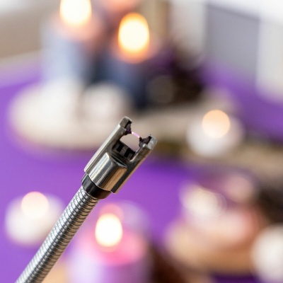 Dispositivo metálico flexível com ponta de metal em fundo desfocado com luzes e velas