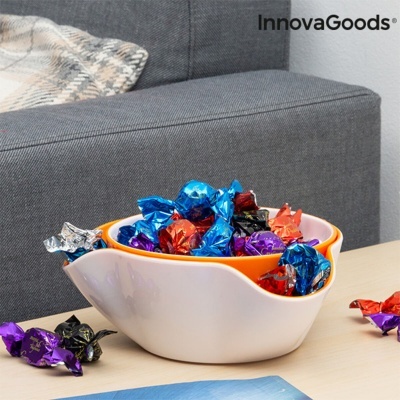 Tigela dupla cerâmica com chocolates coloridos sobre mesa, sofá cinza e manta atrás, texto InnovaGoods