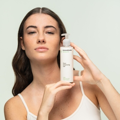 Frasco branco com dispensador de gel de limpeza facial InnovaGoods segurado por mulher com pele clara e cabelo castanho