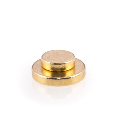 Ímanes redondos dourados empilhados sobre fundo branco