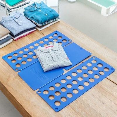 Organizador de roupa azul para dobrar camisas com várias camisas dobradas ao lado.