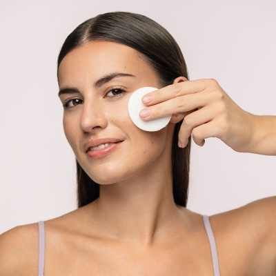 Mulher aplicando disco de algodão no rosto