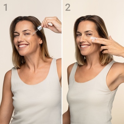 Mulher aplica sérum e creme facial com rosto sorridente e fundo neutro branco