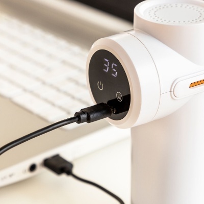 Dispositivo branco com visor digital a mostrar o número 35 e porta USB em uso junto a um teclado branco.