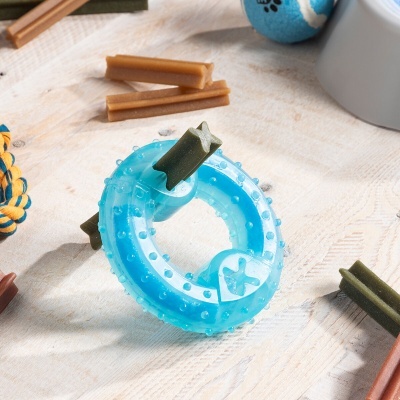 Brinquedo anel azul para cães com pedaços verdes e marrons inseridos, sobre superfície clara
