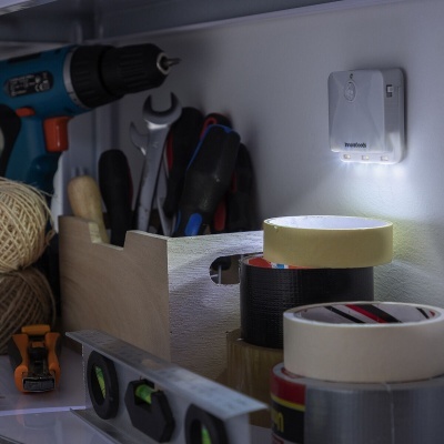 Ferramentas de bricolage incluindo furadeira, fitas adesivas, alicates, nível e lâmpada de parede em oficina.