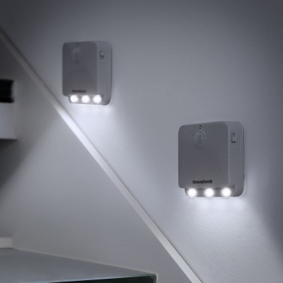Luzes de parede quadradas brancas com LEDs montadas numa parede branca junto a uma escada