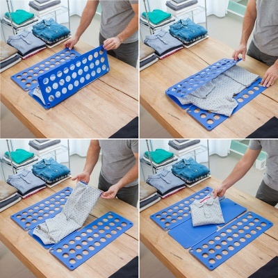 Pessoa a dobrar camisa cinza com organizador azul sobre mesa de madeira