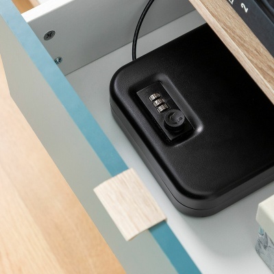 Cofre preto com fechadura de combinação numa gaveta azul clara com detalhes em madeira