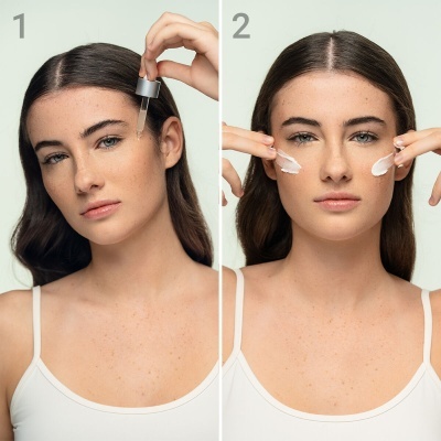 Mulher aplicando líquido com conta-gotas e creme facial nas bochechas num fundo branco