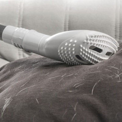 Acessório de aspiração branco colocado sobre tecido castanho com pelos