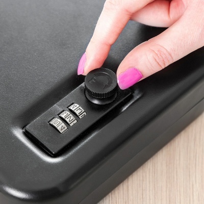 Fecho de combinação numérica preto com botão giratório e mão feminina com unhas rosas