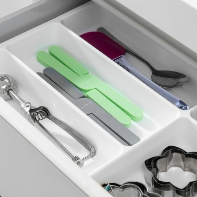 Gaveta branca com utensílios de cozinha variados organizados em divisórias.