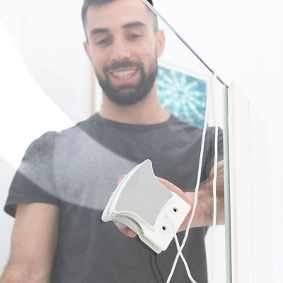 Homem a limpar porta de vidro transparente com dispositivo branco de limpeza elétrica