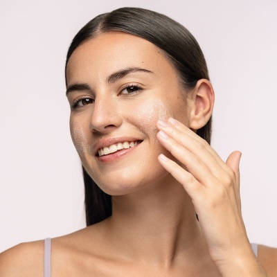 Mulher a aplicar creme facial com o dedo numa mão
