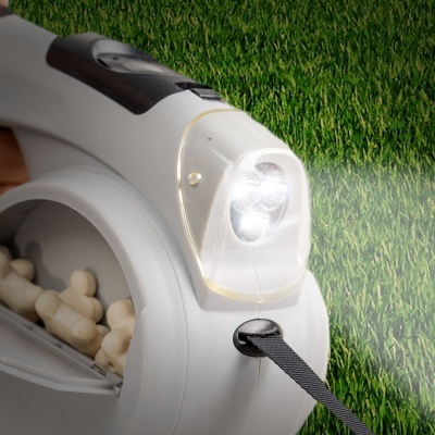 Dispositivo eletrônico branco com luzes LED acesas e alça preta sobre relva sintética