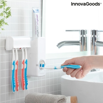 Dispensador automático de pasta de dentes branco com suporte para escovas na parede de azulejos, mão com escova azul em pia branca